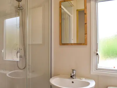a bathroom with a shower and a sink and a mirror at The Beachcomber in Palnackie