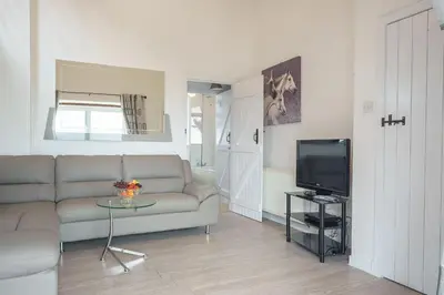 a living room with a couch and a television at Thomas Carlyle Cottage in Thornhill