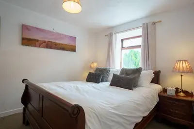a bedroom with a bed with white sheets and a window at Morton Cottage in Thornhill
