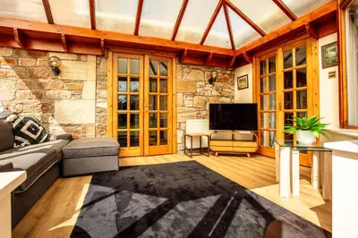 a living room with a couch and a tv at Burnock Lodge with Hot Tub in Ayr