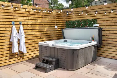 a hot tub in a backyard with a wooden wall at Cottage - Sleeps 4 hot tub & pet friendly in Carlisle
