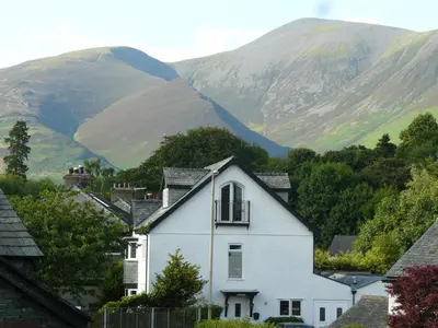 a white house with mountains in the background at Riverside Escape in Keswick