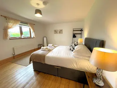 a bedroom with a large bed and a window at Spectacular 7BR House Hot Tub and Gardens in Gretna - Pass the Keys in Gretna Green