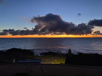 a sunset over the ocean with a building at Southcliff House in Portpatrick