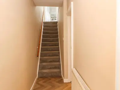 a stairway in a home with white walls and wooden floors at Bay Tree Cottage in Keswick