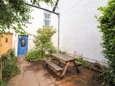 a wooden picnic table in front of a house at Bay Tree Cottage in Keswick