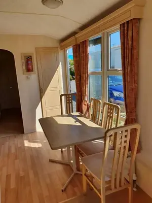 a dining room with a table and chairs and a window at Serenity in Monreith