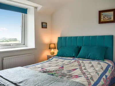 a bedroom with a bed with a blue headboard and a window at High Spy in Bassenthwaite