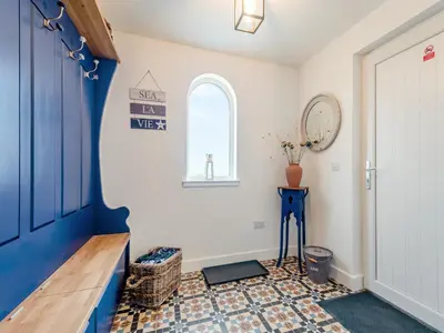 a hallway with a blue door and a window at Seascape Barn in Kirkcolm