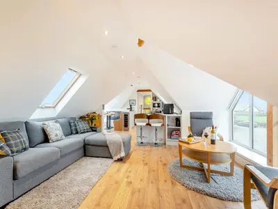 a living room with a couch and a table at Seascape Barn in Kirkcolm