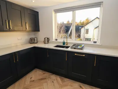 a kitchen with black cabinets and a sink and a window at Mallard Cottage in Penrith