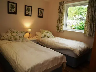 two beds in a room with a window at Seabank Cottage in Rockcliffe