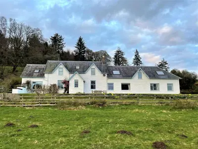 a large white house with a fence in a field at Kenmure Kennels in New Galloway