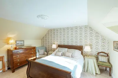 a bedroom with a bed and a dresser and chairs at Kenmure Kennels in New Galloway