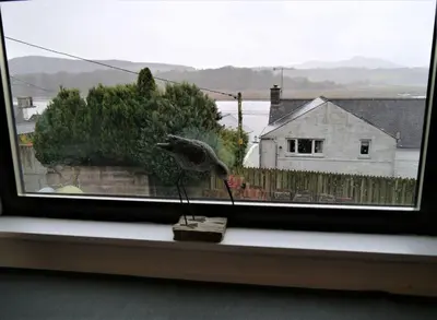 a bird statue sitting on a window sill at Kippford Stables in Kippford