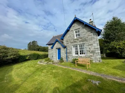 a small stone house with a bench in the yard at Rowantree Cottage in Gatehouse of Fleet