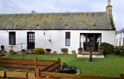 a white house with a wooden fence in front of it at Ernambrie Cottage in Castle Douglas