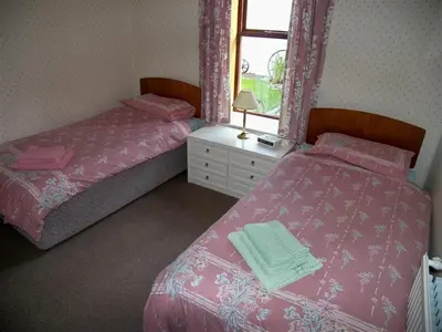 a bedroom with two beds and a window at Ernambrie Cottage in Castle Douglas