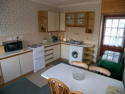 a kitchen with a table and a stove top oven at Ernambrie Cottage in Castle Douglas