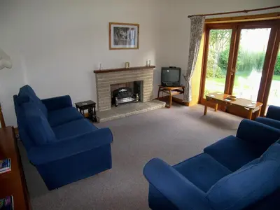 a living room with two blue chairs and a fireplace at Ernambrie Cottage in Castle Douglas