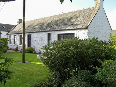 a white brick house with a gray roof at Ernambrie Cottage in Castle Douglas