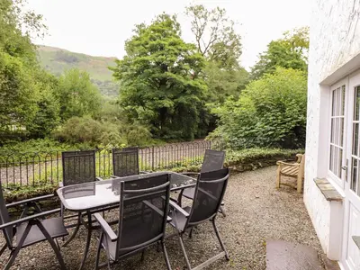 a patio with a table and chairs and a fence at Holly Cottage in Ambleside
