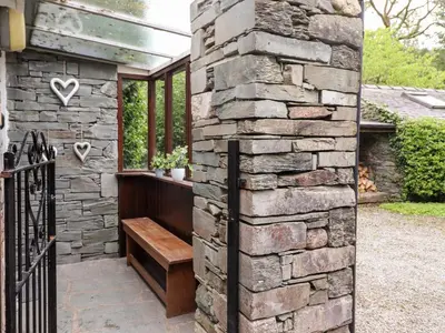 a stone wall with a bench in front of a building at Holly Cottage in Ambleside