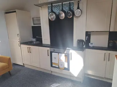 a kitchen with white cabinets and pots and pans at The Snug in Cockermouth