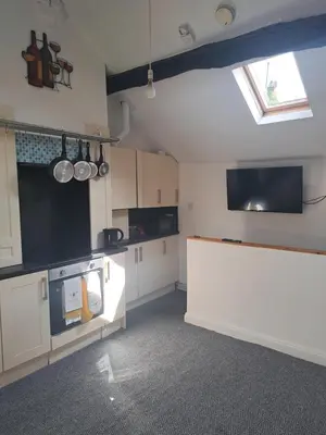 a kitchen with white cabinets and a flat screen tv at The Snug in Cockermouth
