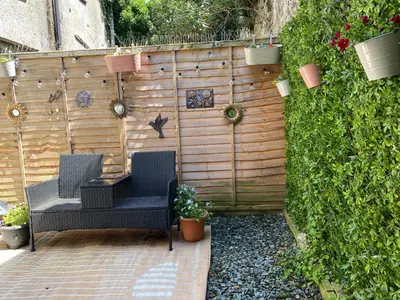 a patio with two chairs and a fence with plants at The Snug in Cockermouth