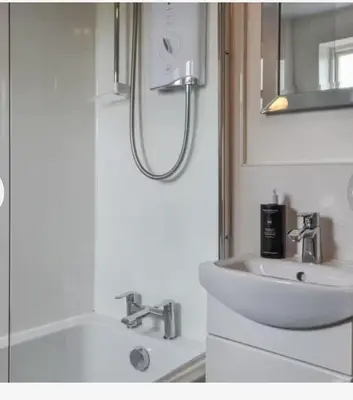 a white bathroom with a sink and a mirror at Roses Cottage cosy countryside home with open fire and mountain views near Scafell in Santon Bridge