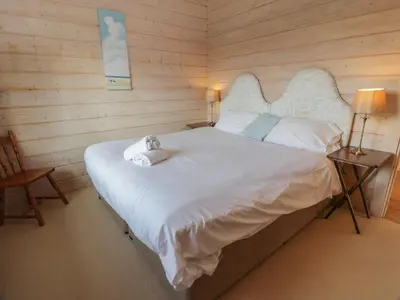 a bedroom with a white bed with two stuffed animals on it at Lapwing Lodge in Dumfries