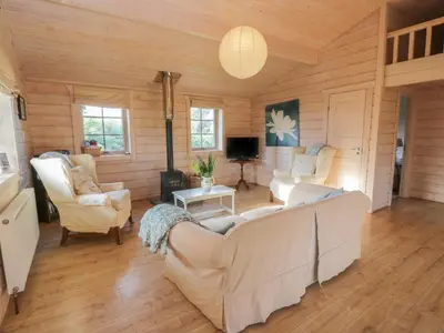 a living room with white couches and a tv at Lapwing Lodge in Dumfries