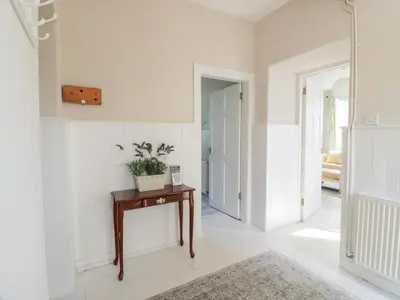 a hallway with white walls and a table with a plant on it at West Lodge in Dumfries