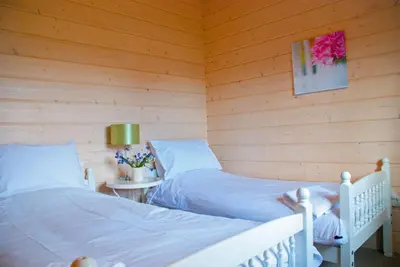 two beds in a room with wooden walls at Skylark Lodge in Dumfries