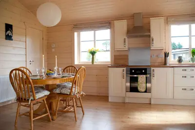 a kitchen with a wooden table with chairs and a stove at Skylark Lodge in Dumfries