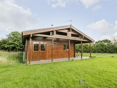 a small wooden cabin in a field of grass at Curlew Lodge in Dumfries