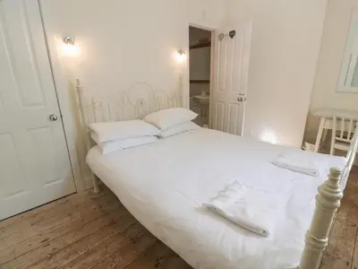 a white bed with white sheets and towels on it at Little Dunbar Cottage in Dumfries