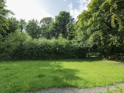 a grassy yard with a bench in the distance at Little Dunbar Cottage in Dumfries