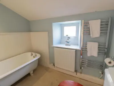 a bathroom with a bath tub and a window at Little Dunbar Cottage in Dumfries