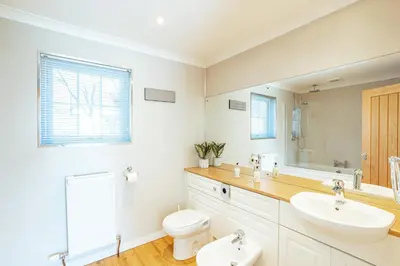 a bathroom with a sink and a toilet and a mirror at Sparrowhawk Cottage with Hot Tub in Newton Stewart