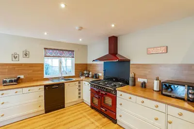 a kitchen with a red stove top oven next to a window at Sparrowhawk Cottage with Hot Tub in Newton Stewart