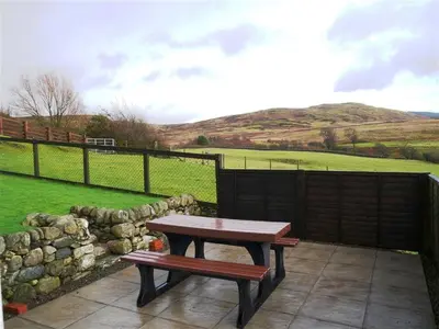 a picnic table and bench on a patio with a field at Laghead Steading Cottage in Gatehouse of Fleet