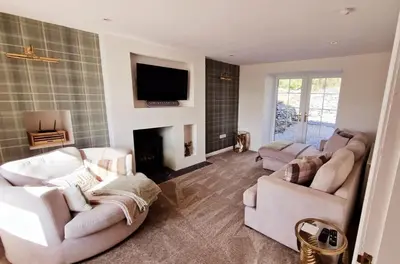 a living room with two white couches and a fireplace at Nordlys Cottage in Newton Stewart