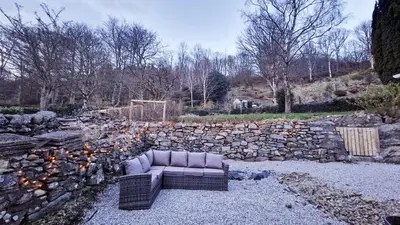 a couch sitting in front of a stone wall at Nordlys Cottage in Newton Stewart