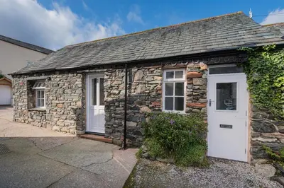 a stone cottage with a white door at cottage 7 old farmhouse mews in Keswick