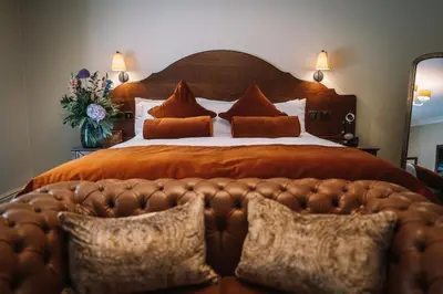 a large bed with a large wooden headboard and pillows at Bridge House Hotel & Silver Howe View Cottage in Grasmere