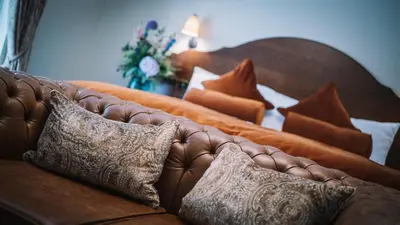 a brown leather couch with pillows on it at Bridge House Hotel & Silver Howe View Cottage in Grasmere
