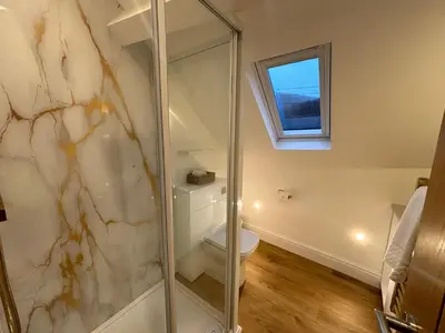 a bathroom with a shower with a toilet and a window at Braithwaite House Rooms in Braithwaite