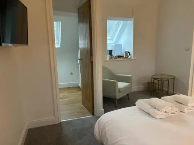 a bedroom with a bed and a chair and a television at Braithwaite House Rooms in Braithwaite